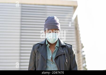 young african man walking through the city wearing the mask Stock Photo