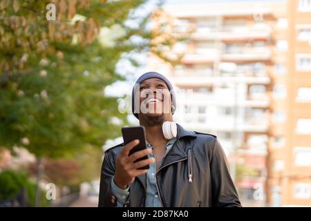 young african man in the city listening to music from his headphones Stock Photo
