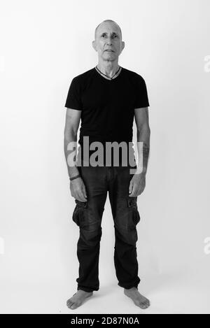 Full body shot of bald senior man standing against white background Stock Photo