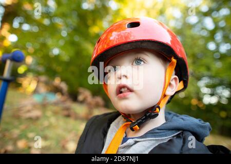 Preschool Age Boy Wearing Red Helmet Looks Up While outside Playing Stock Photo