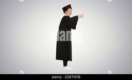 Happy female graduate holding diploma and making selfie on her p Stock Photo