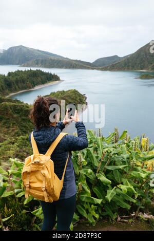 Back view of a young woman enjoying in nature taking a photo Stock Photo