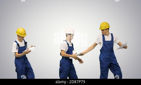 Three young construction workers in hardhats passing on document Stock Photo
