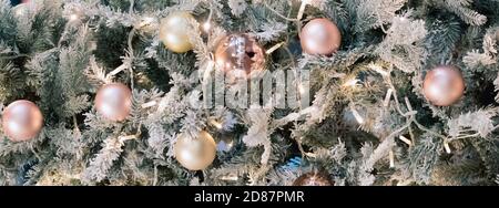 Balls and garlands hanging on pine branches on festive backdrop. Golden baubles on spruce tree. Christmas background. Stock Photo