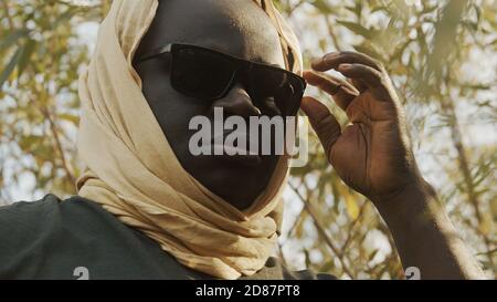 Portrait of african black man with head covering and sunglasses in park. High quality photo Stock Photo