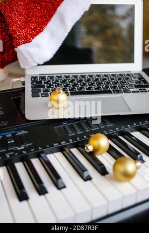 Christmas balls and laptop with santa hat on piano keys. Stock Photo