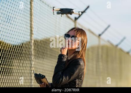 Woman flying drone in forbidden zone. Fly a drone without a license. Fly drone near airport. Drone legislation Stock Photo