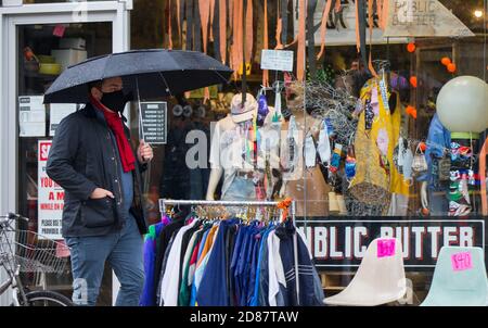 Toronto, Canada. 27th Oct, 2020. A man wearing a face mask walks past a clothing store in Toronto, Canada, on Oct. 27, 2020. Canada hit another grim milestone on Tuesday as the country's death toll of COVID-19 reached 10,001, according to CTV. Credit: Zou Zheng/Xinhua/Alamy Live News Stock Photo