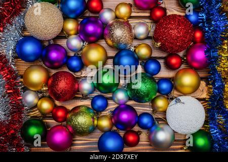 Colorful shiny Christmas balls and tinsel on wooden table background. Close-up view of Xmas holiday decoration Stock Photo