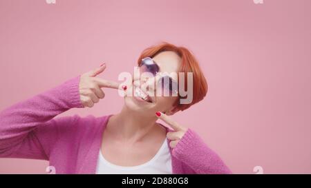 Attractive middle aged woman with red hair pointing fingers on her white teeth. High quality photo Stock Photo