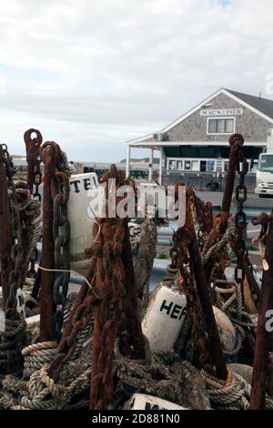 A pile of nautical gear, mostly anchors, sits in from of Mac's seafood restaurant on Wellfleet, Massachusetts pier. Stock Photo