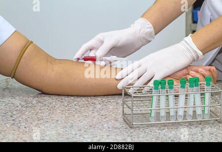 Blood test from venous vein  of patient by female doctor in white medical gloves and many tube on   the marble table Stock Photo