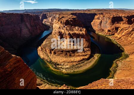 The iconic Horseshoe Bend in late afternoon light contrasts with the emerald and blue water of the Colorado River. Arizona. Stock Photo