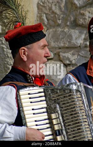 Older Polish man plays the accordion on a street in the Old Town of Krakow, Poland. Stock Photo