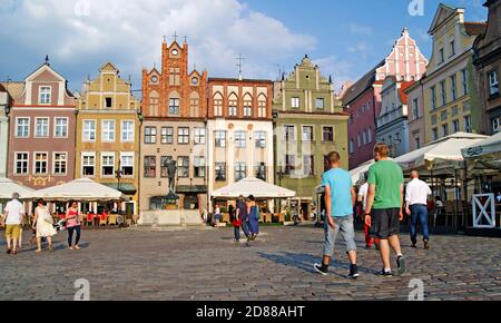 People walk around the architecturally rich old market square in the old town of Poznan, Poland during the summer. Stock Photo