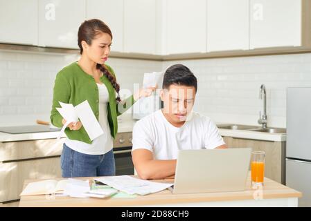 Upset young couple with financial bills having conflict in home interior