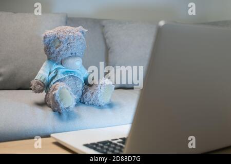 Bangkok / Thailand - October 12 2020 : Teddy bears wearing blue sweater using the laptop in the living room at night. Stock Photo