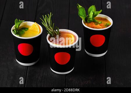 Three cargboard take away cups with fruit tea on dark background Stock Photo