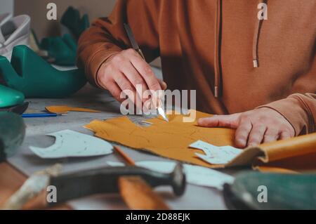Shoemaker cutting patterns using knife from leather Stock Photo