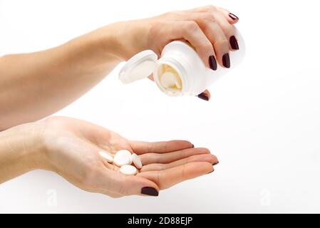 white pills in white plastic jar. COVID-19. Medical mask on a hand with white background. Medicine pills or Vaccine against the virus. Stock Photo
