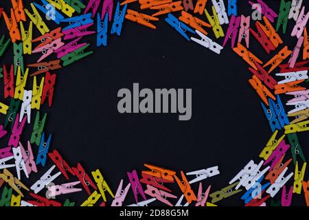 Multicolor wooden pins frame on black background with copy space in the middle Stock Photo