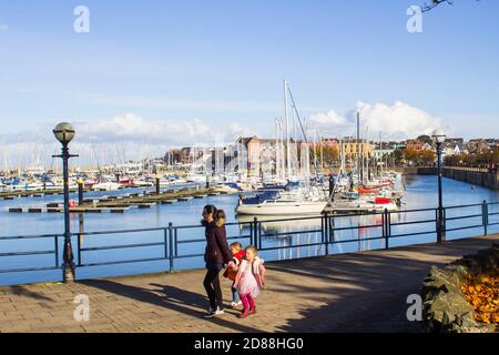 23 October 2020 A mother and children walk the promenade beside the modern marina and its boats in Bangor County Down Northern Ireland on a beautiful Stock Photo