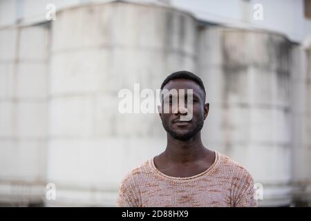 Handsome black man posing for camera. Medium shot. Outdoors. Blurred background. Stock Photo