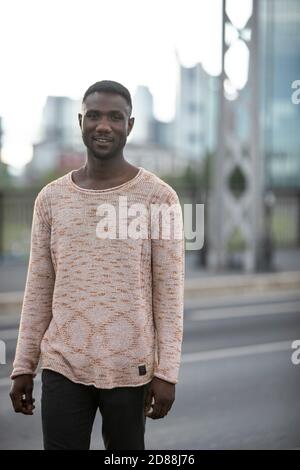 Handsome black man wearing sweater outdoors in city. Portrait. Three quarter length. Looking at camera. Stock Photo