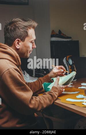 Shoemaker cutting patterns using knife from leather Stock Photo