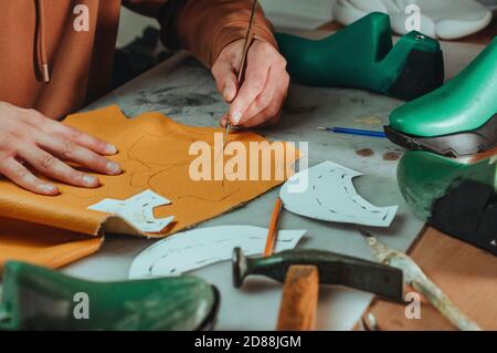 Shoemaker cutting patterns using knife from leather Stock Photo