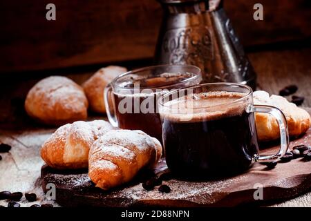 Espresso coffee in a glass cup with small croissants, coffee maker, vintage wooden background, selective focus Stock Photo