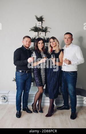 Funny caucasian company of young caucasian friends celebrate Christmas together in beautiful clothes Stock Photo