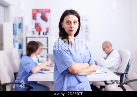 Portrait of medical nurse smiling looking at camera in hospital conference room. Friendly medical practitioner in clinic meeting room, robe, specialist. Stock Photo