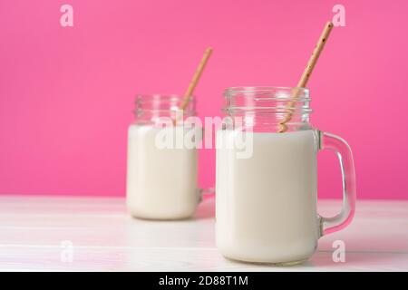 Glass Jars With Flavoured Milkshakes Against Pink Background Stock Photo Alamy