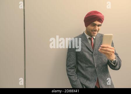 Young handsome Indian Sikh businessman wearing turban while exploring the city Stock Photo