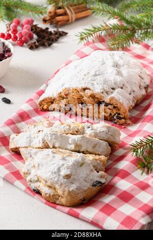 Christmas cutted stollen with raisin and candied fruit on white background. Close up. Tasty traditional German holiday bread. Vertical format. Stock Photo