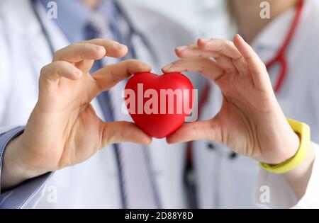 Doctors cardiologists hold red toy heart in clinic closeup Stock Photo