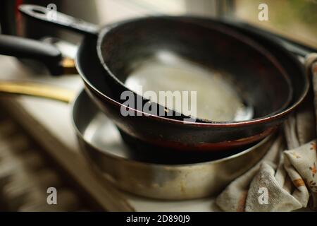 Set of old dirty pans and a towel on the windowsill. Stock Photo