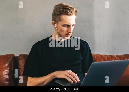 Mobile developer in earphones, programmer writes program code on a laptop Stock Photo