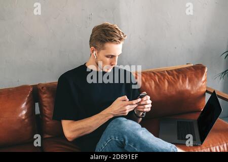 Mman mobile developer in earphones using smartphone, testing application Stock Photo
