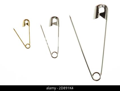 A directly above shot of three metal safety pins in a row on a white background. Stock Photo
