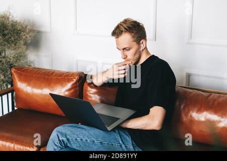 Mobile developer in earphones, programmer writes program code on a laptop Stock Photo