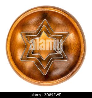 Star shaped cookie cutters in a wooden bowl. Three hexagram shaped biscuit cutters, made of tin, tools to cut out a cookie dough. Stock Photo