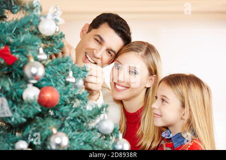 Happy family decorating Christmas tree at Christmas Stock Photo