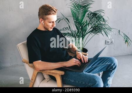 Mobile developer in earphones, programmer writes program code on a laptop Stock Photo