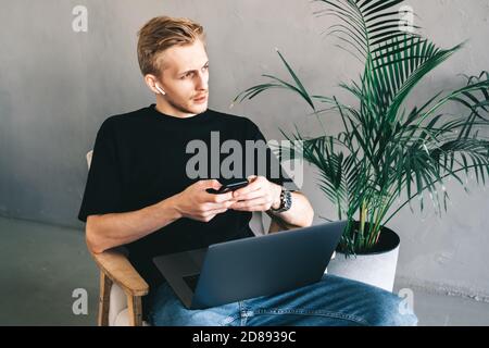 Mman mobile developer in earphones using smartphone, testing application Stock Photo