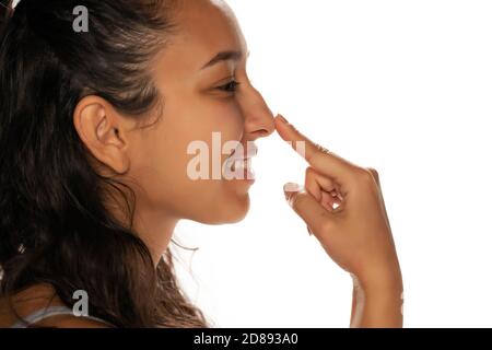 Profile of happy young indian woman touching her nose on white background Stock Photo