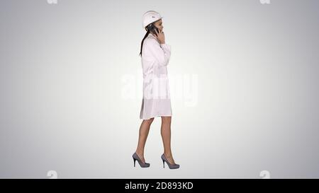 Female science engineer making a call while walking on gradient Stock Photo