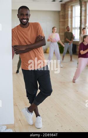 Portrait of African young dancer smiling at camera with people exercising in the background in dance studio Stock Photo