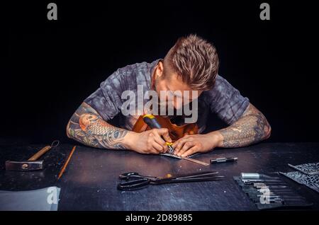 Leather Worker wording with leather goods at workplace Stock Photo